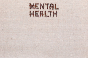 Mental health words from coffee beans on linen canvas, arranged top center