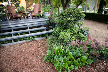 the wooden chairs on a wooden podium in the garden among the plants