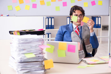 Young male handsome employee in conflicting priorities concept 