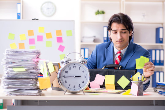 Young male handsome employee in conflicting priorities concept 