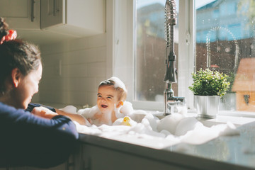 Baby having a bath in the kitchen sink