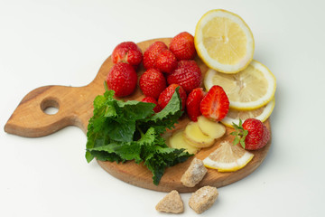Mojito set: lemon, fig, mint and strawberry on a wooden cutting board