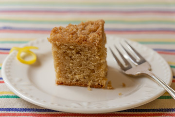Lemon crumb cake on white plate with striped background