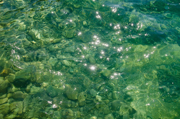 Abstract sea background, colorful ripples of water surface, distorted stone bottom under water