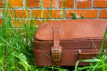 Old shabby suitcase against the background of a brick wall