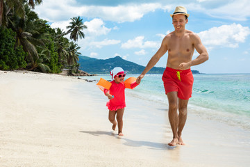 Smiling Man Running With His Daughter On The Beach