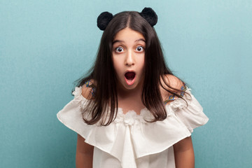 Portrait of shocked beautiful brunette young girl with black long straight hair in white dress...