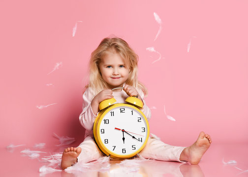 Lovely blonde toddler playing with alarm clock
