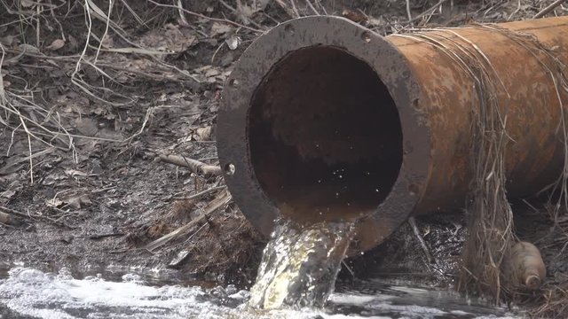 Dirty water flows and foams from a big rusty pipe. Water pollution