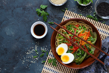 Obraz na płótnie Canvas Noodles with vegetables and eggs in bowl on dark background. Top view with copy space. Asian food.