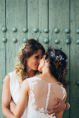 Portrait of a proud couple kissing each other with white wedding dresses