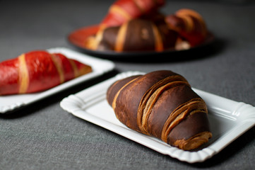 chocolate and red croissants lie on plates on a gray cloth, close-up buns
