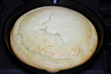 Cornbread in a cast iron skillet resting on the stove top.