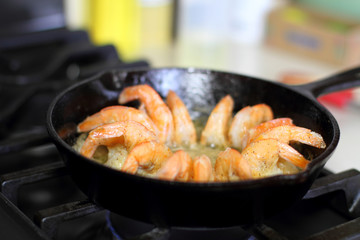 Shrimp cooking in butter and garlic in a cast iron skillet on the stove.