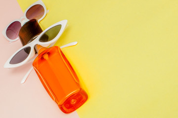 Bottle sunblock on bright square yellow and pink background. The concept of the resort at sea, summer time. Top view, flat lay, minimalism, copy space