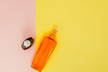 Bottle sunblock on bright square yellow and pink background. The concept of the resort at sea, summer time. Top view, flat lay, minimalism, copy space