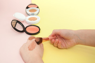 Make up products spilling on to a bright yellow and pink background with copy space