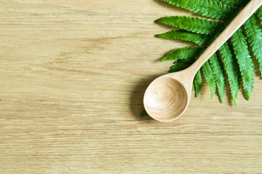 Wooden Ladel and fern leaf on wood surface: concept of nature food