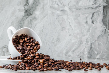 Black coffee in cup and coffee beans on marble background. Top view, space for text