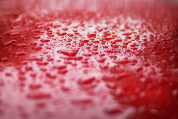 Close up water drops on red car serface for background