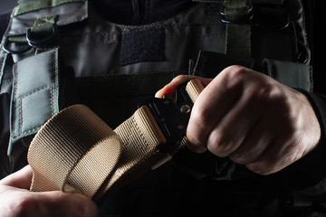 Soldier in tactical vest holding military belt view closeup. - obrazy, fototapety, plakaty