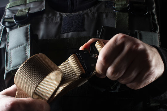 Soldier in tactical vest holding military belt view closeup.