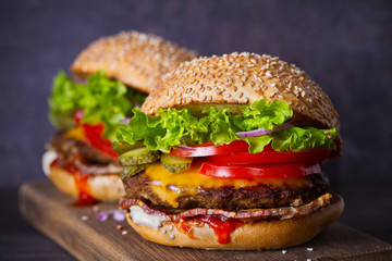 Delicious homemade beef burgers with bacon on wooden chopping board. horizontal