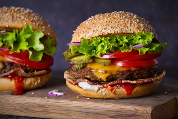 Delicious homemade beef burgers with bacon on wooden chopping board. horizontal