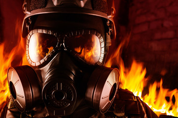 Warrior soldier in gas mask in fire closeup.