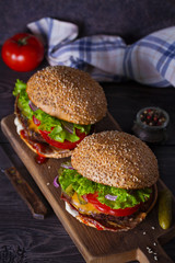 Delicious homemade beef burgers with bacon on wooden chopping board. vertical
