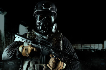 Warrior soldier in gas mask and rifle on black background.