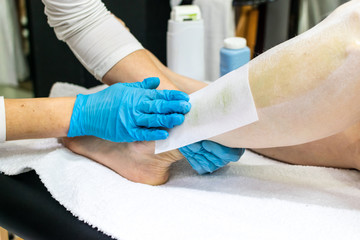 Cold wax legs depilation with hair removal paper strips. Body, health care