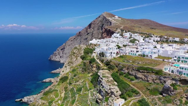 Aerial drone video of iconic and picturesque main village (chora) of Folegandros island featuring castle and built on top of steep hill overlooking the Aegean blue sea, Cyclades, Greece