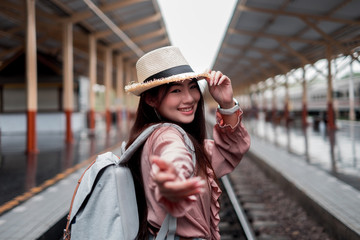 Smiling woman traveler looking camera with backpack on holiday relaxation at the train station,relaxation concept, travel concept