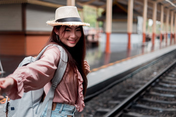 Smiling woman traveler looking camera with backpack on holiday relaxation at the train station,relaxation concept, travel concept