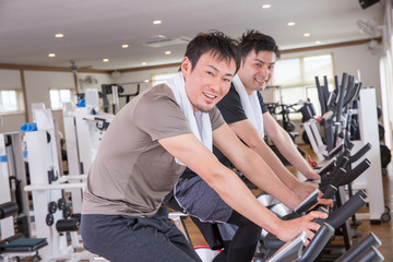 スポーツジムで自転車をこぐ男性