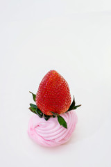 strawberry lying on top of a round pink marshmallow on a white background