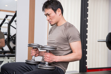 スポーツジムでダンベルをあげる男性