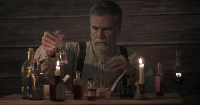 A man skilled in apothecary working with his bottled medicinal concoctions and making notes in his journal.