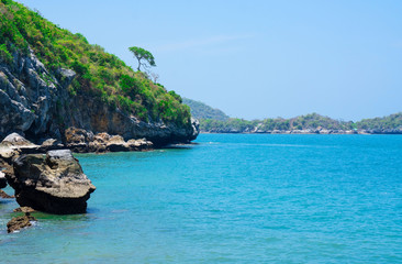 Fototapeta premium At seaside in summer ,waves on stone beach shore . blue sea blue sky background&nbsp;.Travel, Vacation and Holiday concept . Tropical beach .