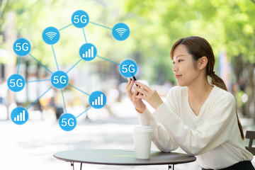 オープンカフェでスマートフォンを使う女性