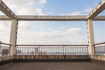 Platform with cement columns and gold railings at the top of high-rise buildings against a blue sky background