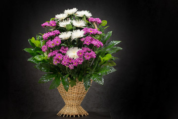 Ritual funeral basket with flowers on a black background The flower arrangement of the flowers in...