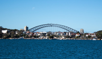 Fototapeta premium City Harbourside houses at Robinsons Point Birchgrove Sydney Australia with Harbour bridge in background against blue sky