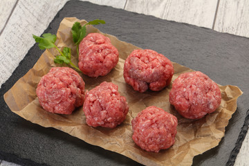 Raw meatball over wooden background