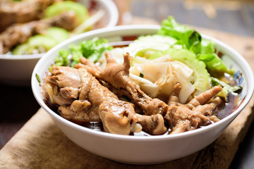 Rice noodles soup with stewed chicken wing and feet in a bowl