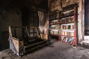 Fototapeta na wymiar Sofa and book case burnt after a fire. Disaster, Ignorance, Brain Washing, Desolation