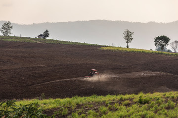 agricultural tractor working in vast farm on mountain plain, Mar Ramat, tak, Thailand