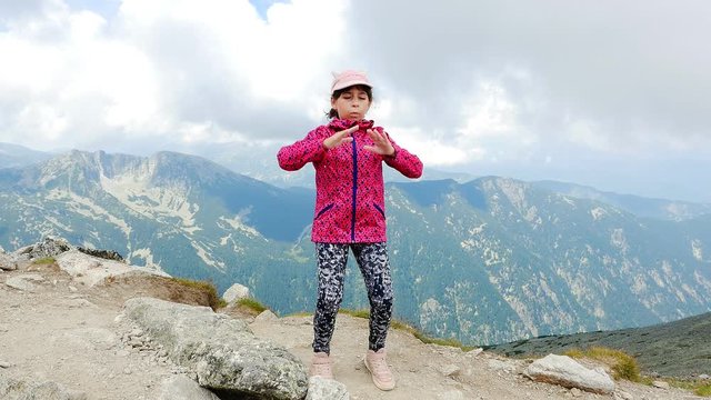 Little girl is relaxing while admiring the beautiful view from the highest Musala Peak in Rilla National Park, Bulgaria