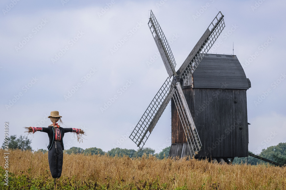 Canvas Prints Scarecrow in front of wooden traditional post mill from late 18th century in Olsztynek heritage park in Masuria region of Poland